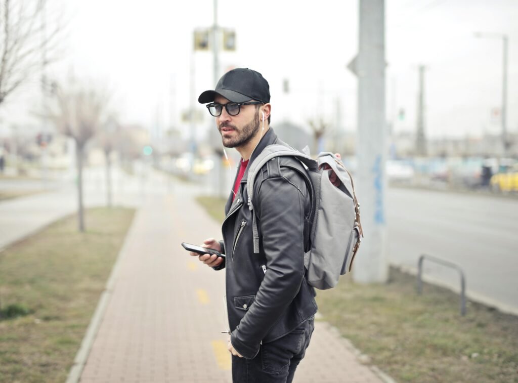 A fashionable young man in Budapest checking his smartphone on a busy street.